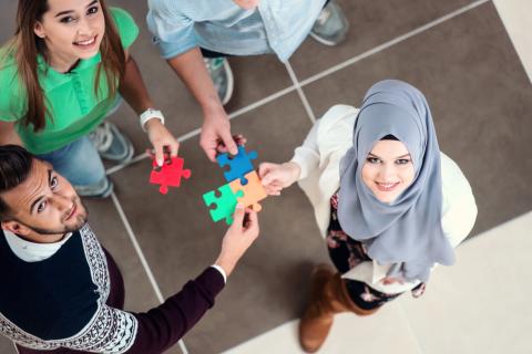 A group of people linking together jigsaw pieces representing integration